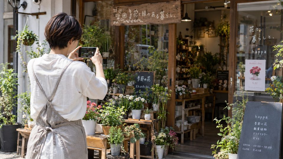 植物の写真をスマホで撮影している女性スタッフの後ろ姿
